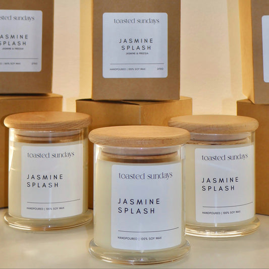 Candles labeled 'Jasmine Splash' with matching boxes on a neutral background
