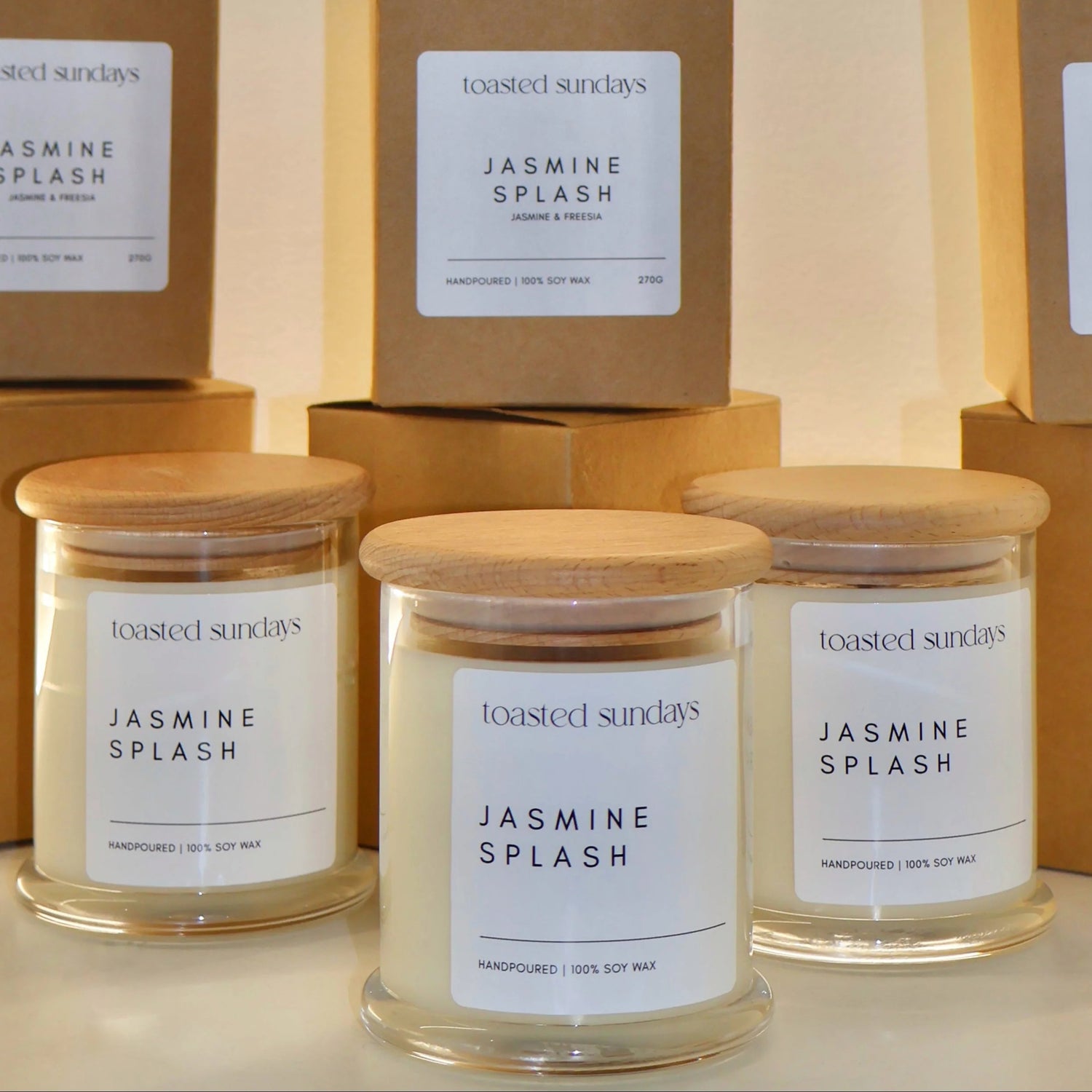 Candles labeled 'Jasmine Splash' with matching boxes on a neutral background