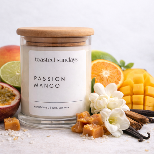Candle labeled 'Passion Mango' by 'toasted Sundays' with fruit and flowers on a white background
